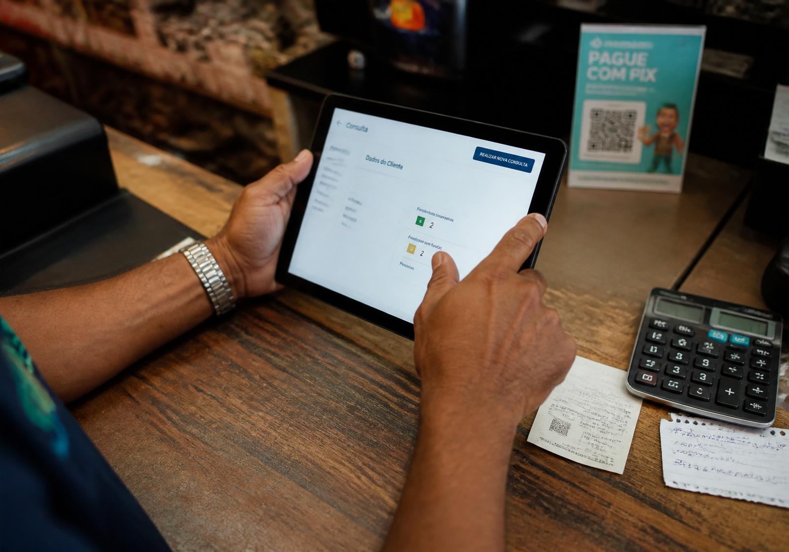 Lojista consultando CPF em tablet no balcão
